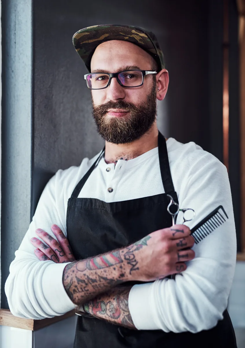 Barbero profesional con peines y tijeras en su barbería