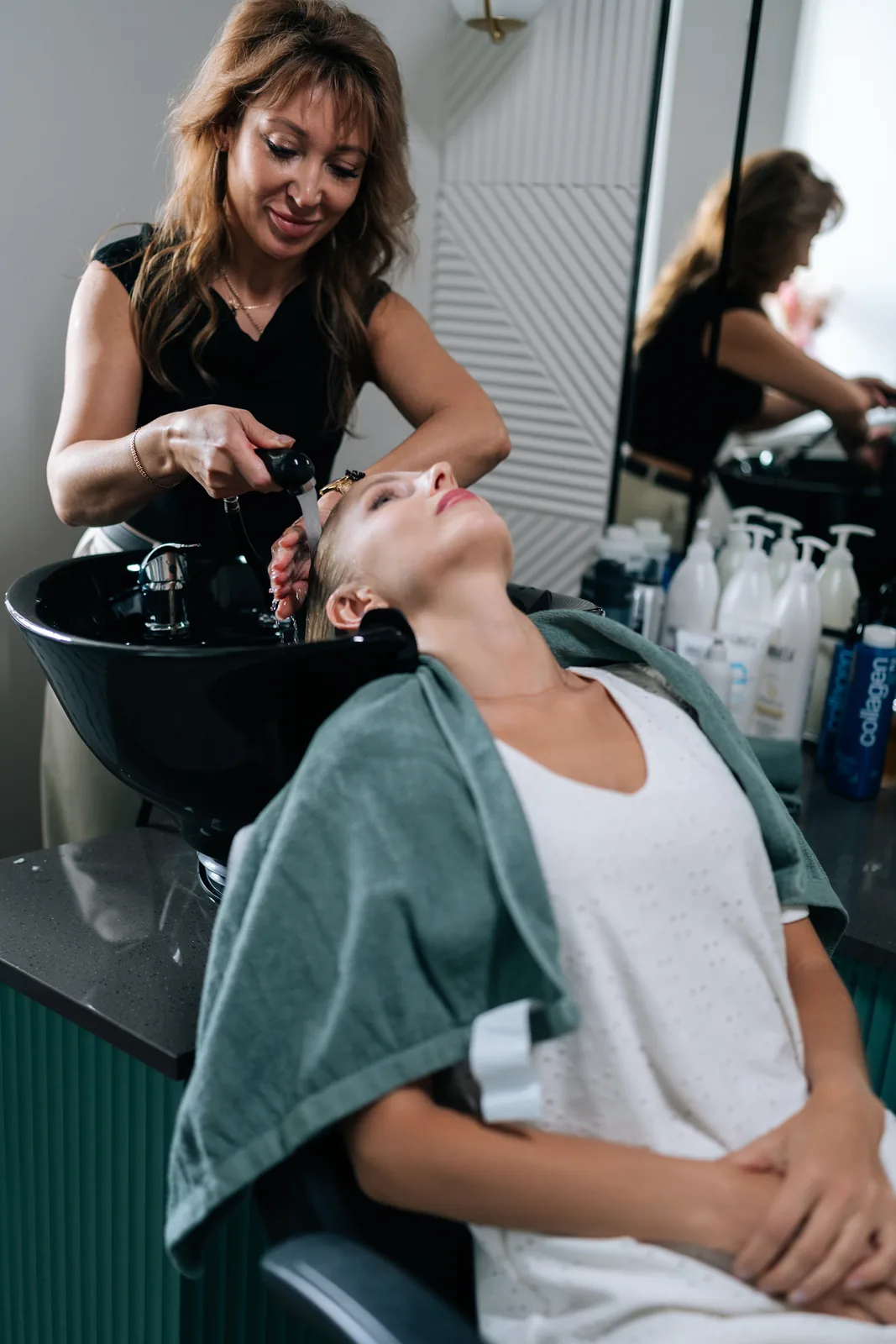 Peluquera lavando el cabello a un cliente — con las manos ocupadas