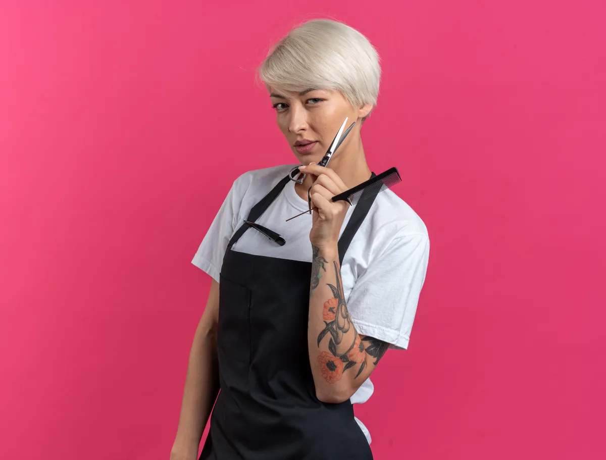 Peluquera con tijeras sobre fondo rosa